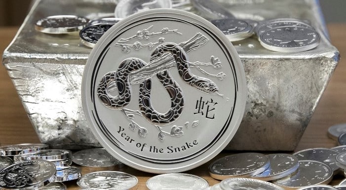 Year of the Snake silver coin in front of a 15-kilogram silver ingot, part of an investment precious metals collection.